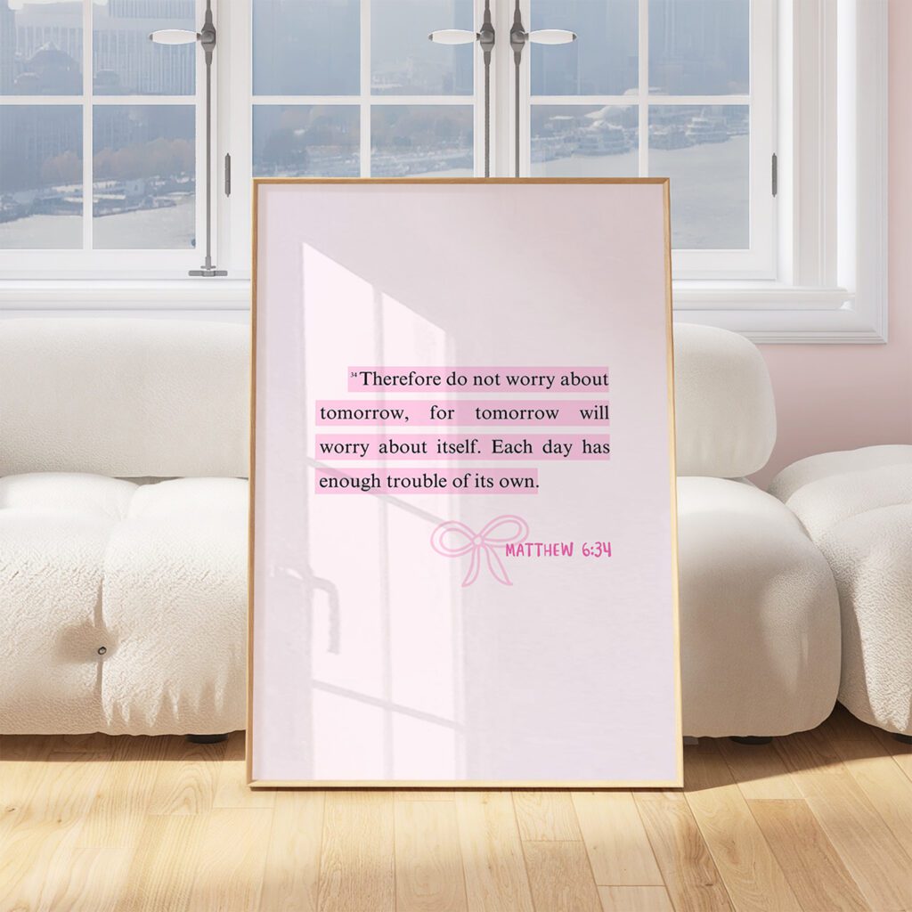 Framed Matthew 6:34 quote on white couch, large windows in the background.
